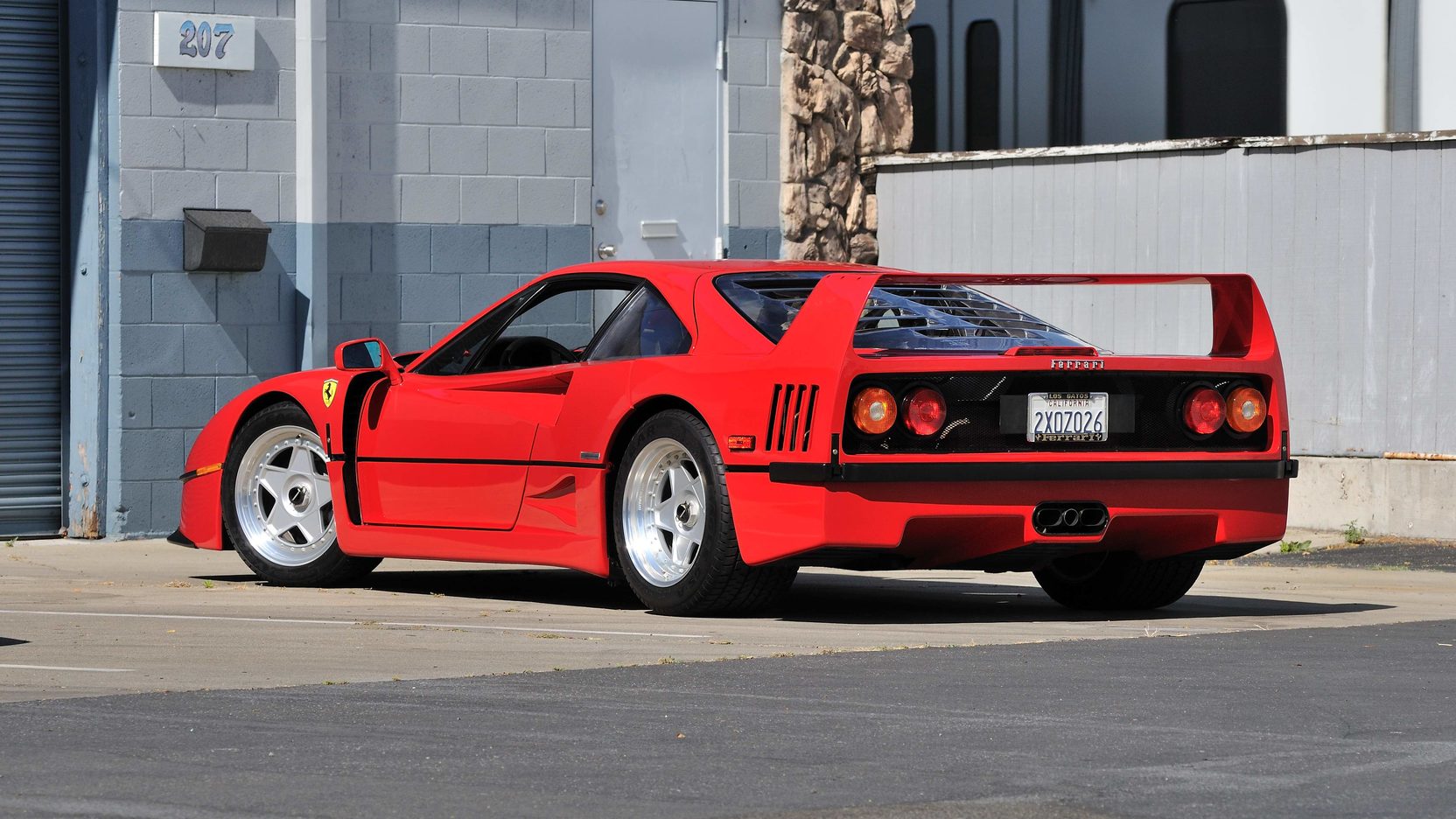 Red Ferrari F40 sitting in parking lot behind building