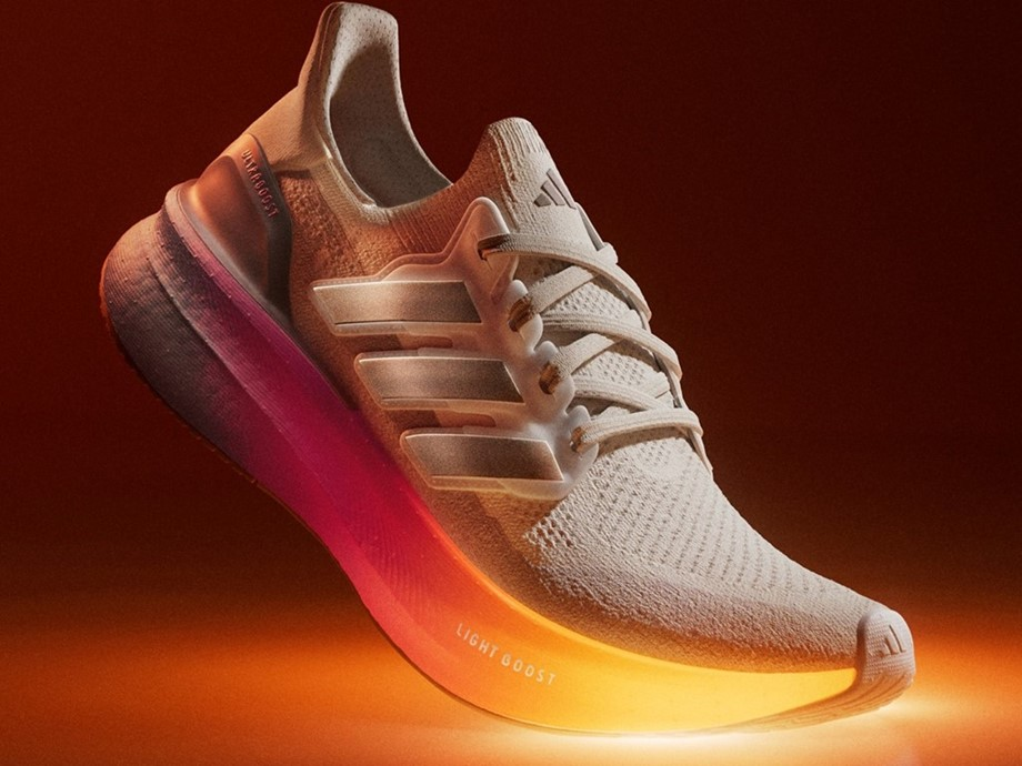 A rendering of an Adidas Ultraboost 5 sneaker in white with a pink and yellow hued outside. The empty shoe is positioned as if someone were stepping in it, with the toe region touching the ground creating a bit of golden light. 