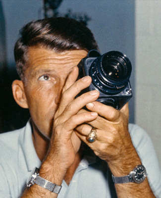 Wally Schirra with his space-bound Hasselblad 500c. We've got no idea why he's wearing two watches.