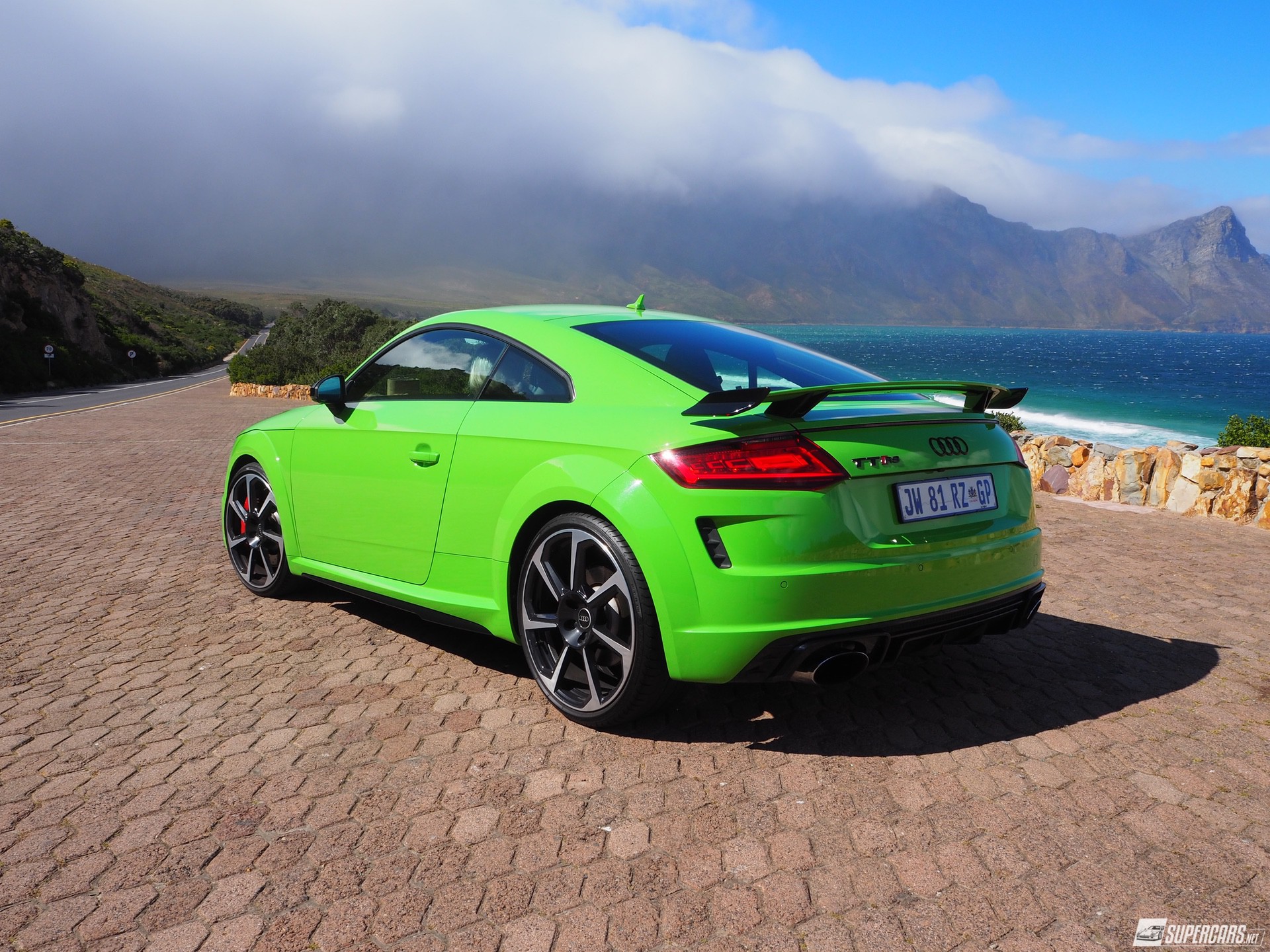 Green 2022 Audi TT-RS parked on side of road near ocean and mountains