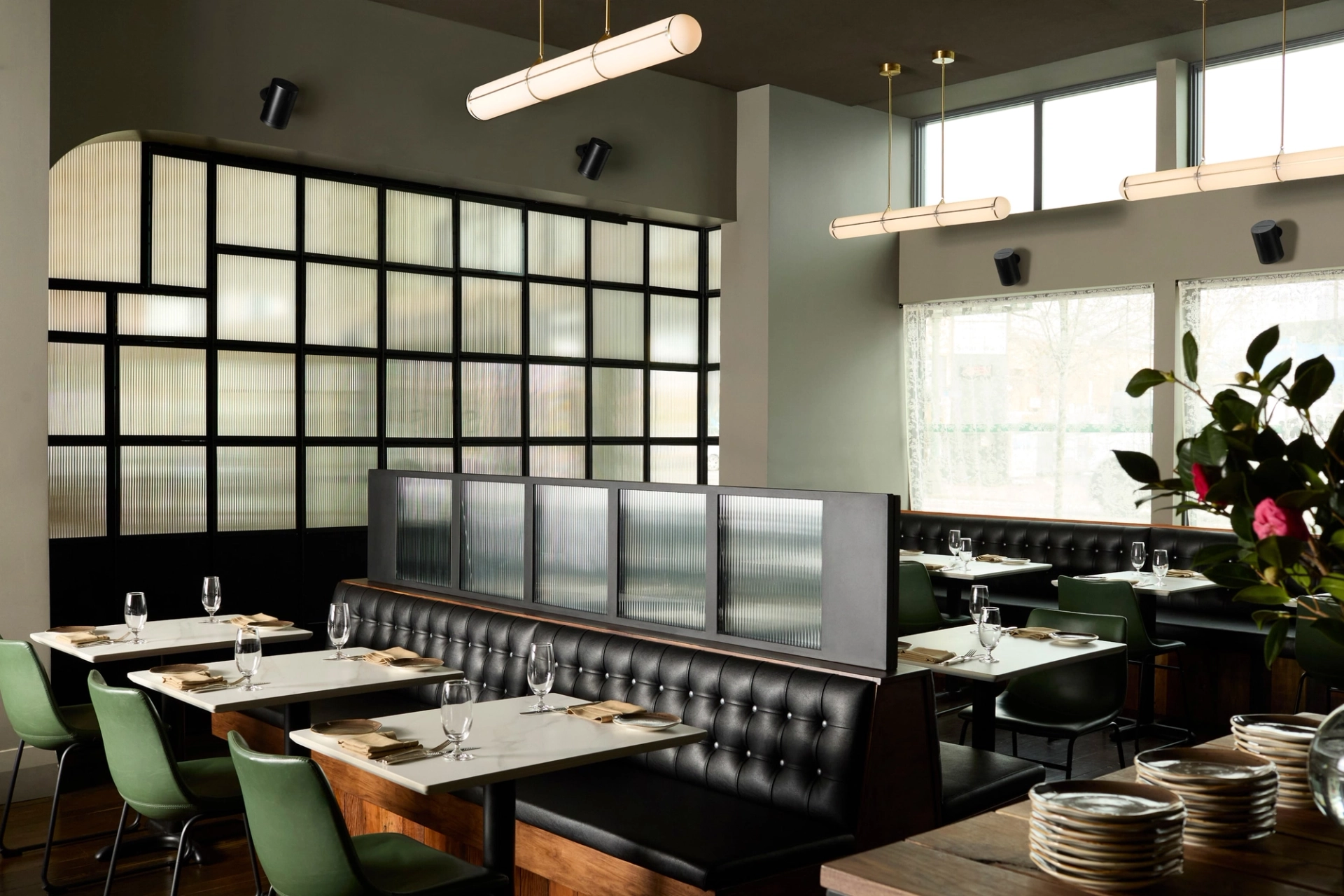 Picture of a stylish modern restaurant dining room with Sonos Era 100 Pro speakers mounted high above the windows