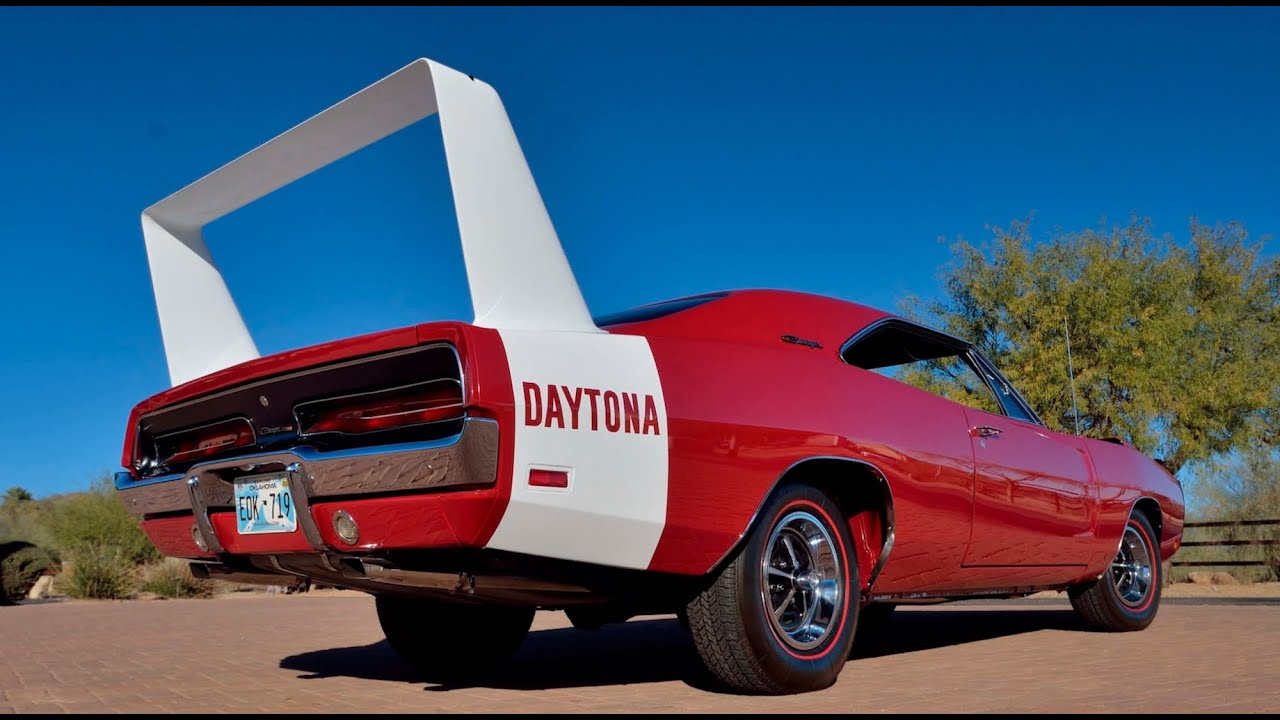 Red and white 1969 Dodge Charger Daytona sitting outside near tree