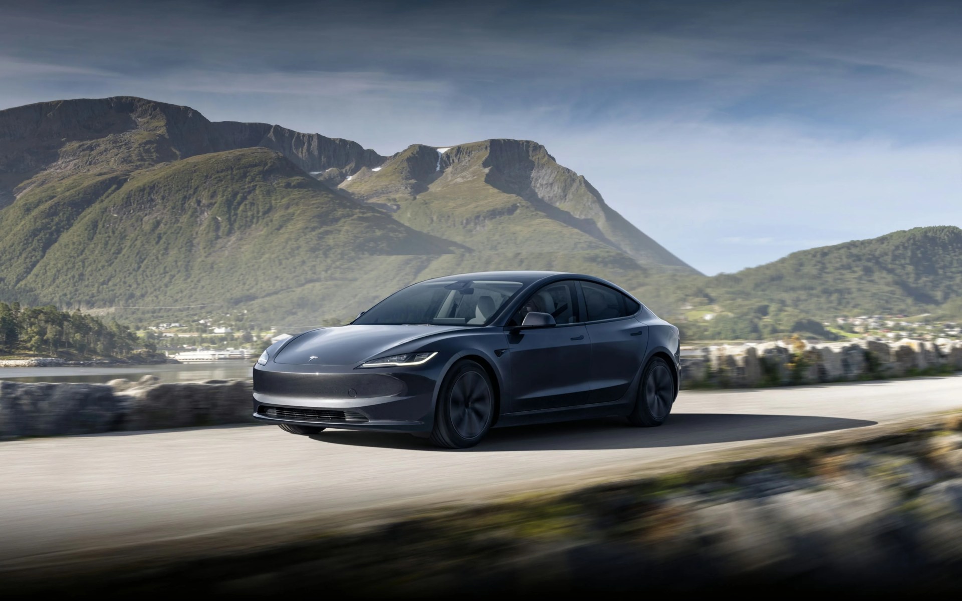 tesla model 3 2024 in gray on a road in front of a mountain