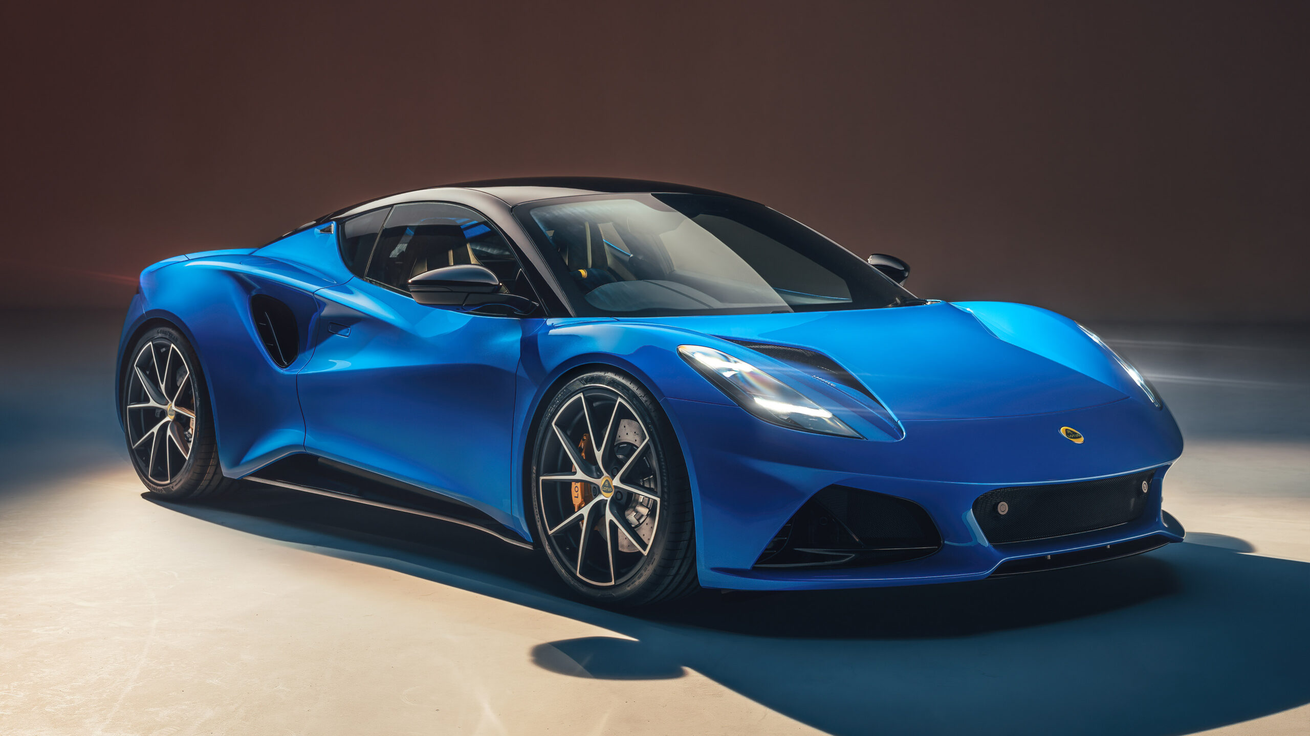 A side view of a blue Lotus Emira, in studio lighting