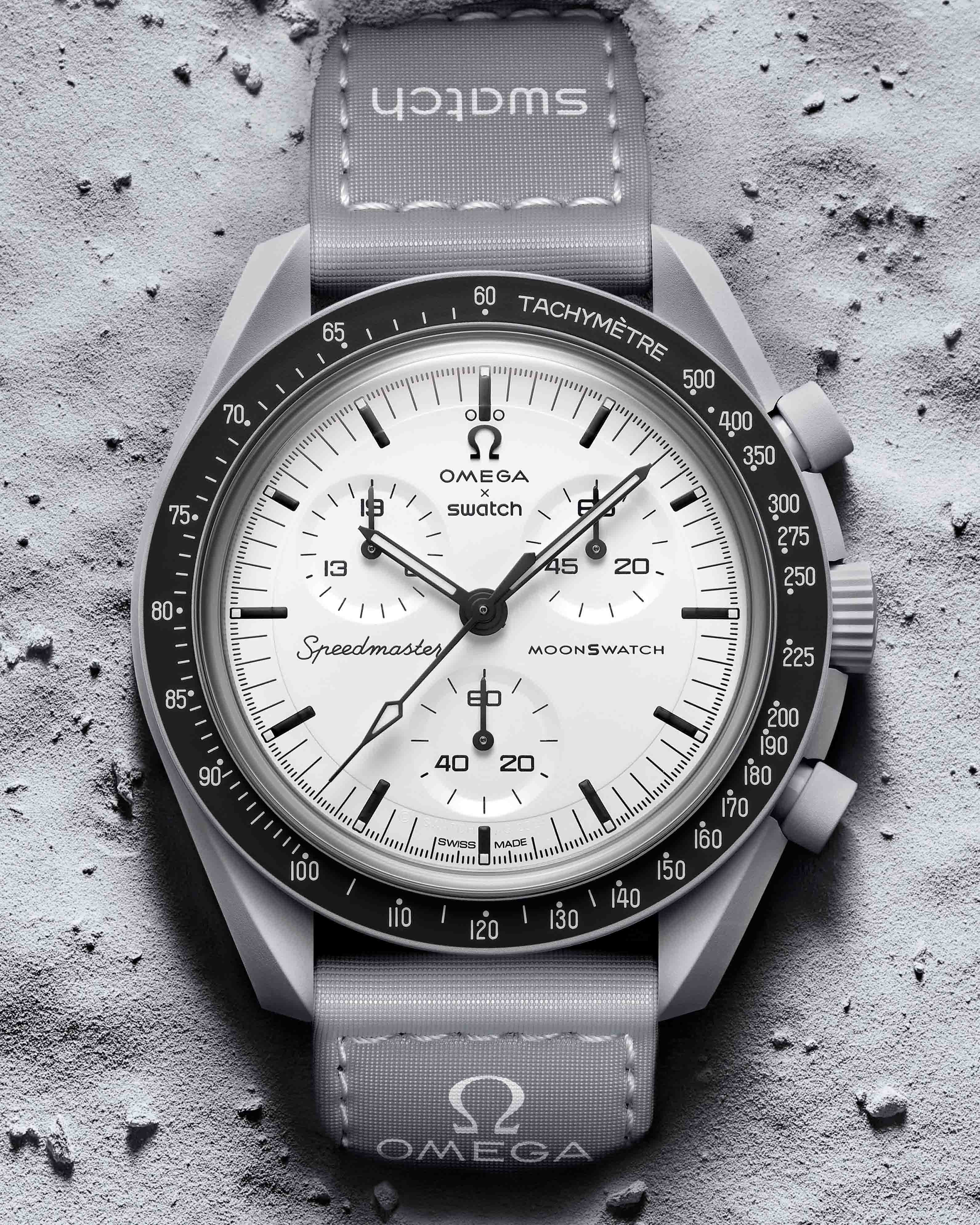 a gray swatch chronograph watch laying in gray sand